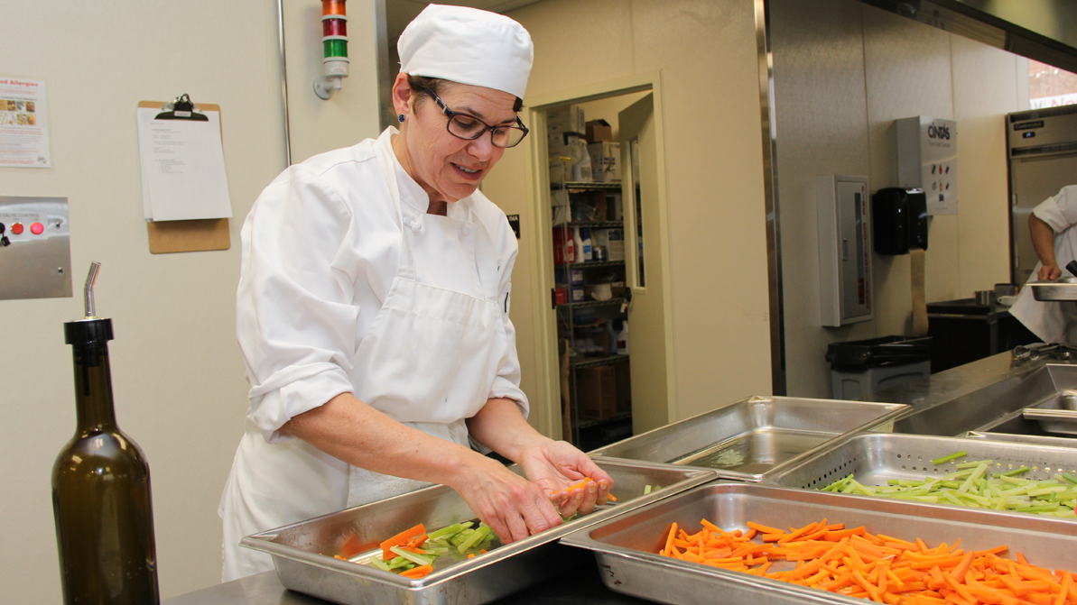 A female adult student works in a culinary environment